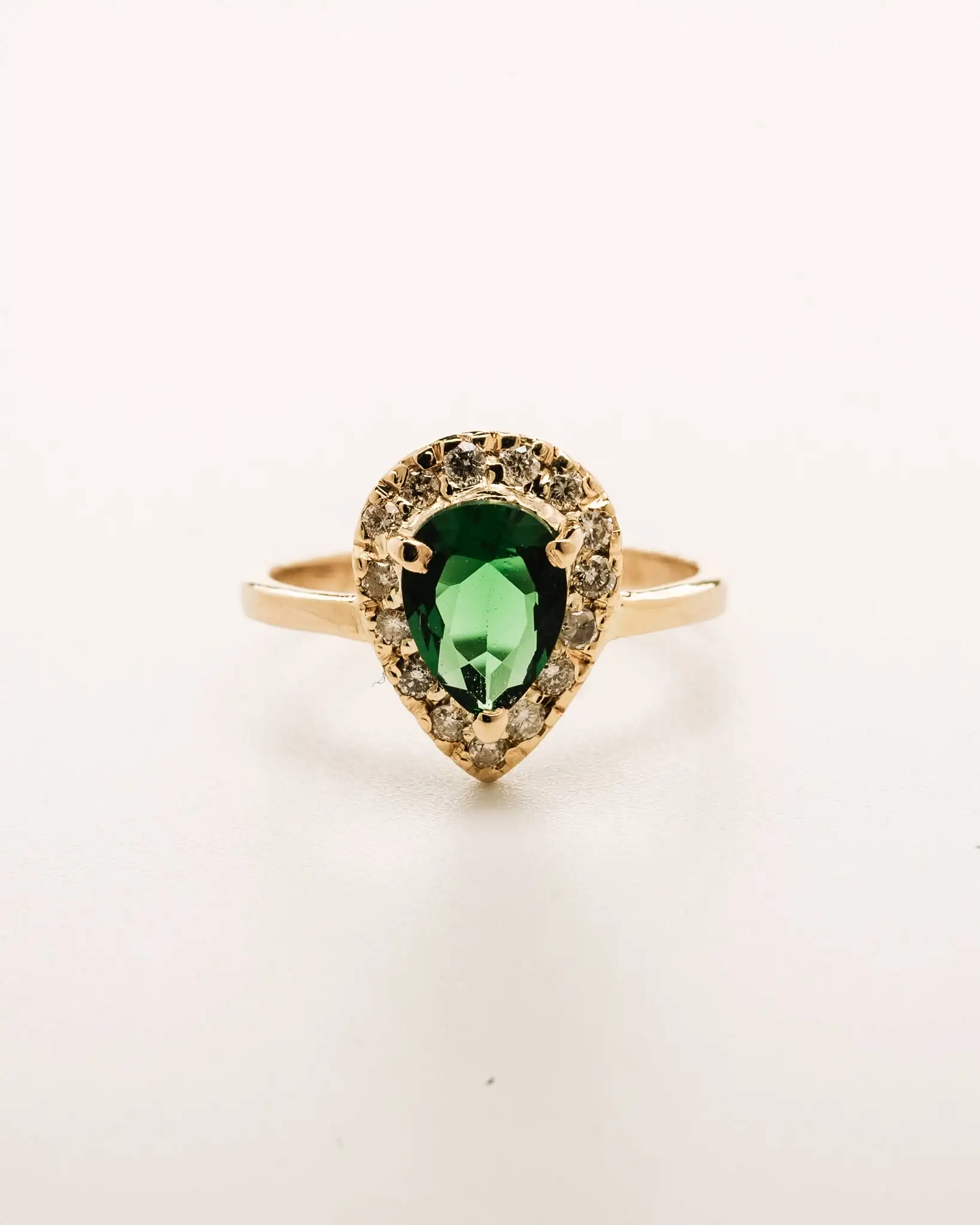 A pear-cut emerald ringed by a diamond halo
